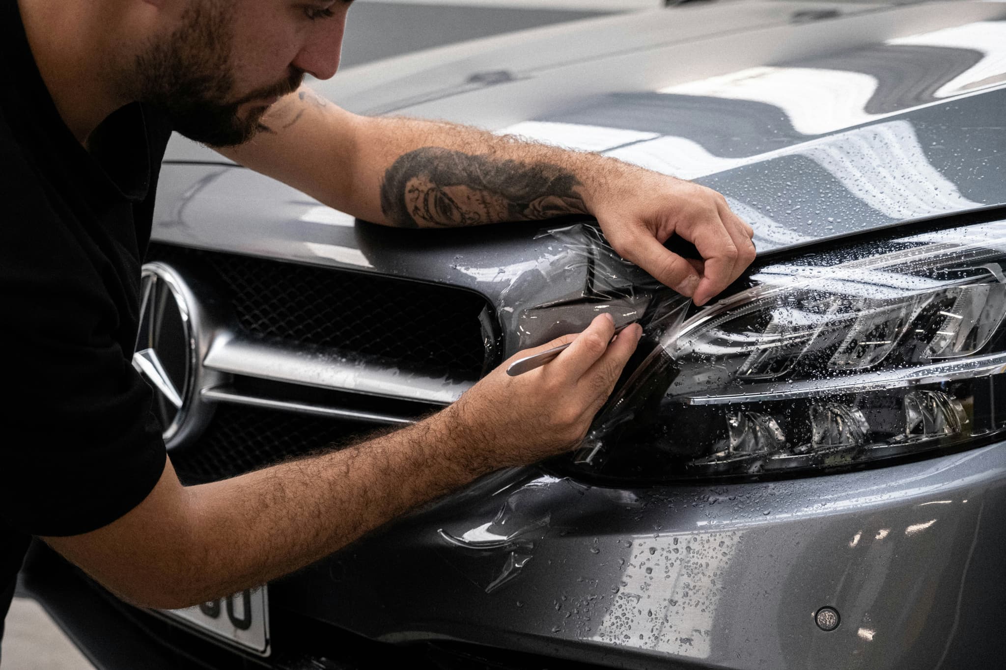 Detailer applying paint protection film to a Mercedes headlight