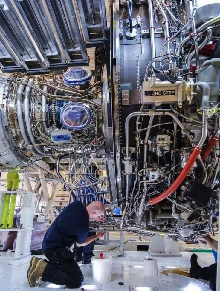 Technician inspecting an aircraft turbine engine at close range.
