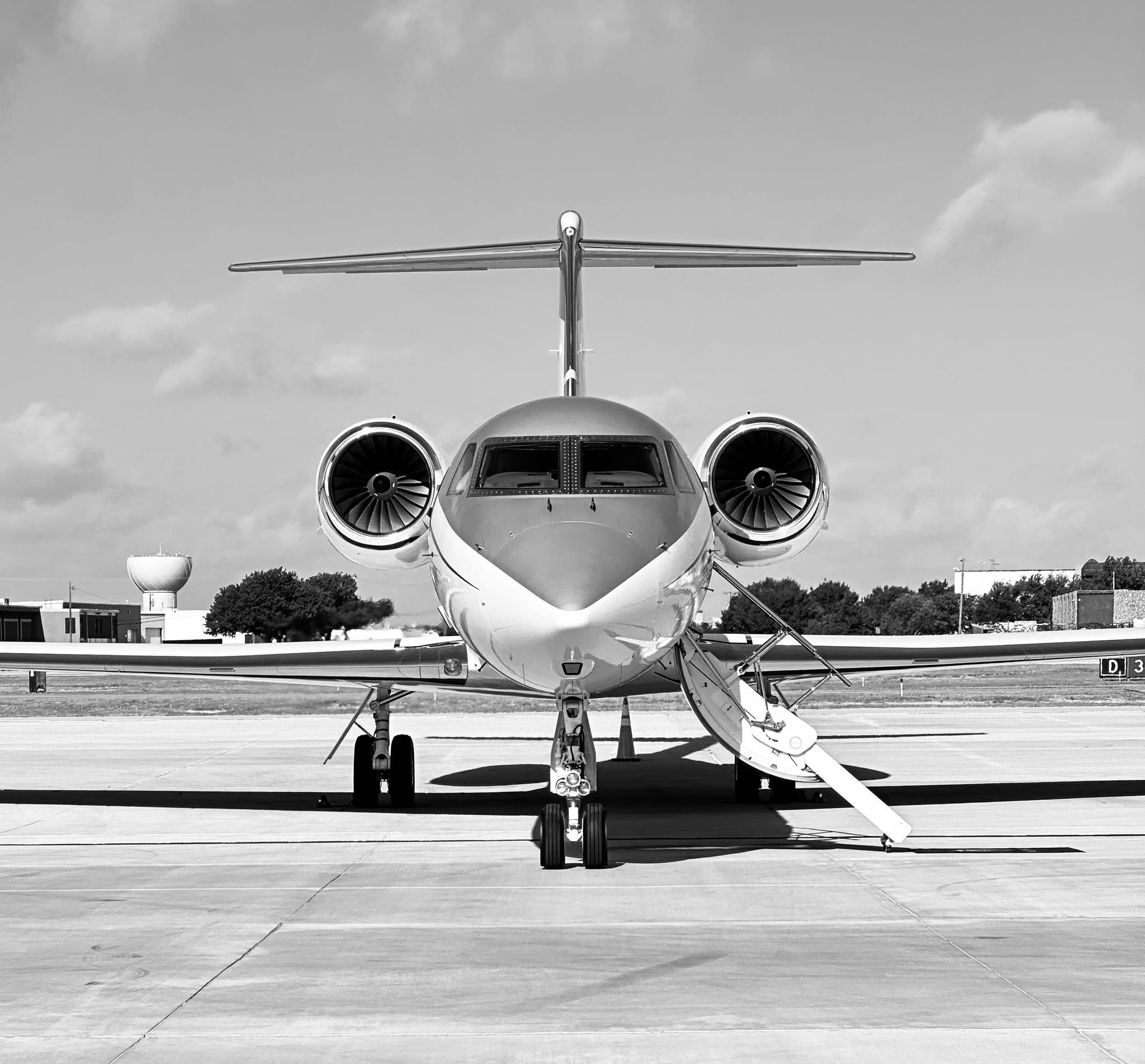 Business jet parked on the tarmac, front view, black and white.