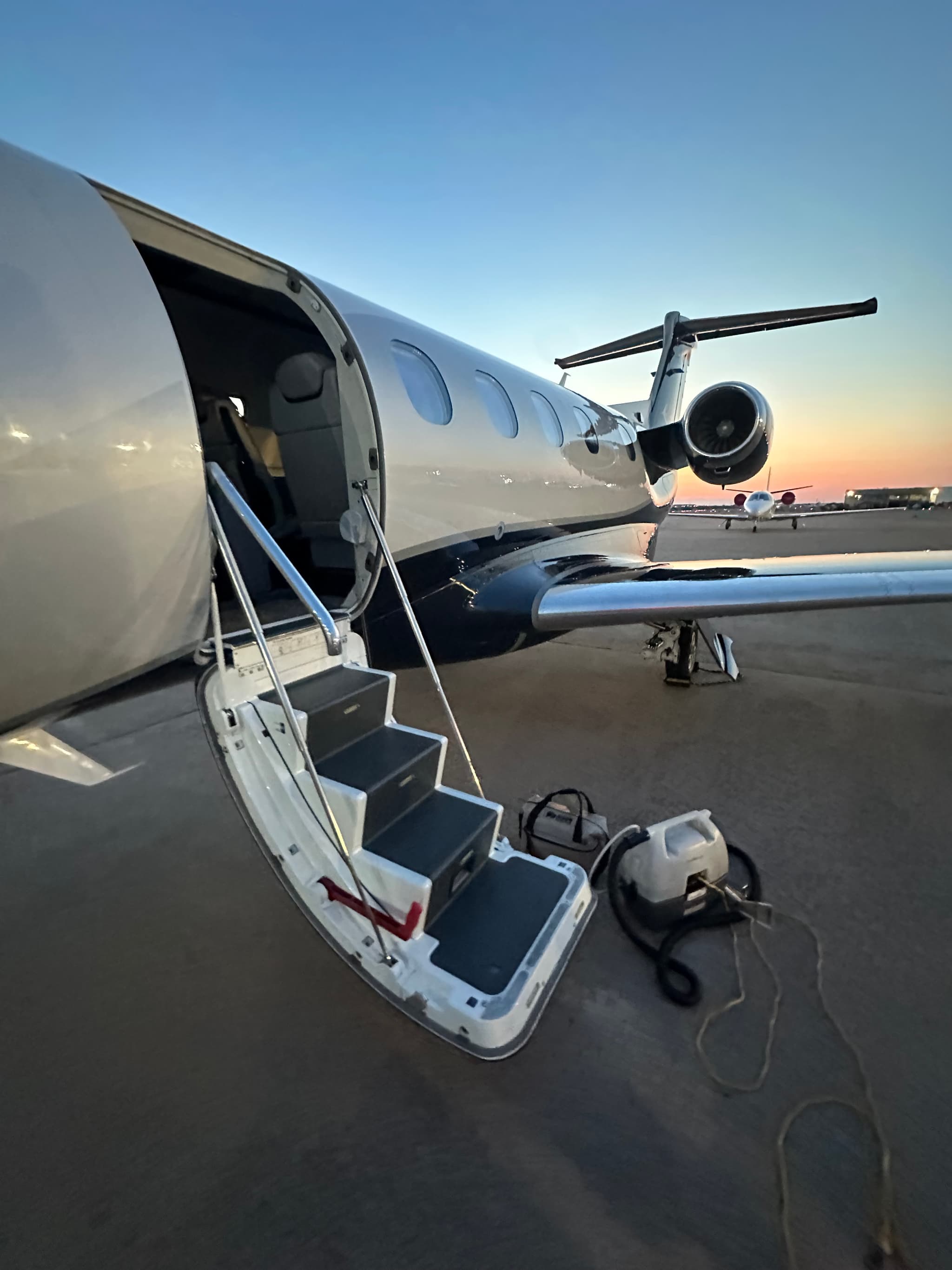 Business jet with airstair deployed and aviation detailing equipment on the tarmac