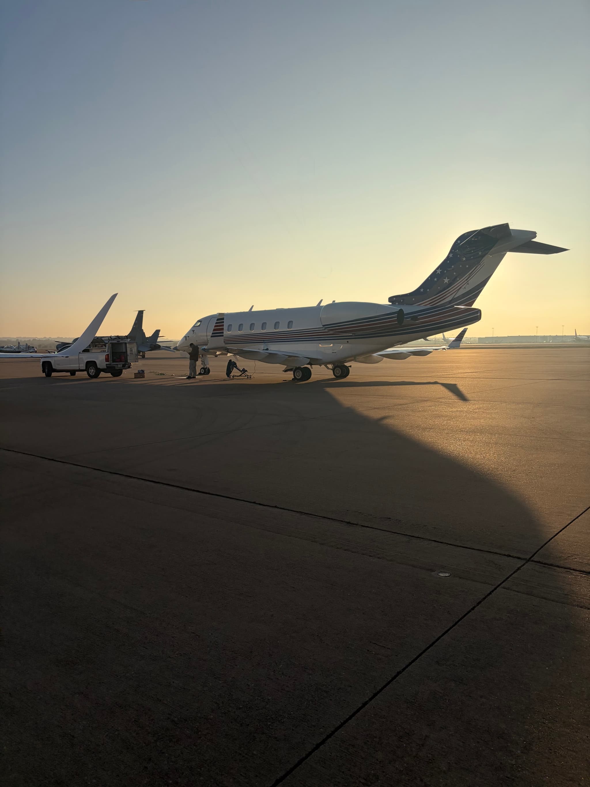 Business jet with US flag tail livery on the tarmac, service crew preparing the aircraft