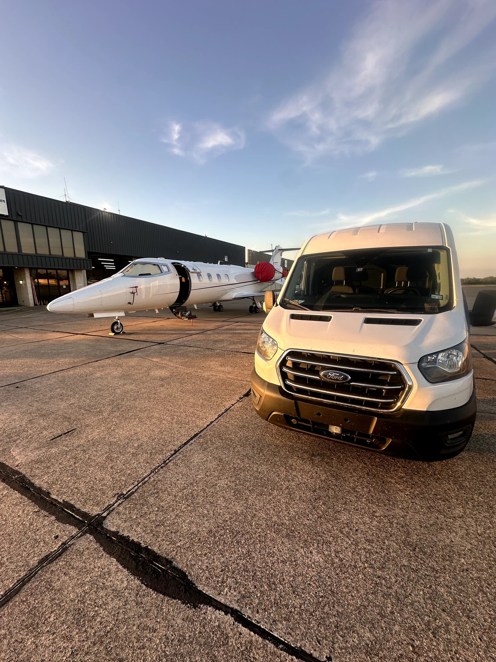 Aviation detailing service crew van parked beside a Citation X jet on a hangar tarmac